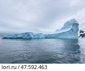 A huge high breakaway glacier drifts in the southern ocean off the coast of Antarctica at sunset, the Antarctic Peninsula, the Southern Arctic Circle, azure water, cloudy weather. Стоковое фото, фотограф Vladimir Drozdin / Фотобанк Лори
