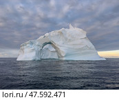 A huge high breakaway glacier drifts in the southern ocean off the coast of Antarctica at sunset, the Antarctic Peninsula, the Southern Arctic Circle, azure water, cloudy weather. Стоковое фото, фотограф Vladimir Drozdin / Фотобанк Лори
