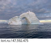 A huge high breakaway glacier drifts in the southern ocean off the coast of Antarctica at sunset, the Antarctic Peninsula, the Southern Arctic Circle, azure water, cloudy weather. Стоковое фото, фотограф Vladimir Drozdin / Фотобанк Лори