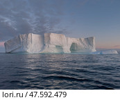 A huge high breakaway glacier drifts in the southern ocean off the coast of Antarctica at sunset, the Antarctic Peninsula, the Southern Arctic Circle, azure water, cloudy weather. Стоковое фото, фотограф Vladimir Drozdin / Фотобанк Лори