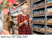 Elderly woman chooses multi-colored pigments for her future clay or ceramic dishes in specialized store. Стоковое фото, фотограф Яков Филимонов / Фотобанк Лори