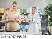 Pregnant woman choosing dermatologically tested shampoo for safe use. Стоковое фото, фотограф Яков Филимонов / Фотобанк Лори