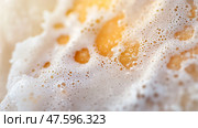 Frothy texture of a freshly poured beverage captured close-up with shimmering bubbles and golden tones in warm natural light. Стоковое AI-изображение, AI-художник Сергей Толмачёв / Фотобанк Лори
