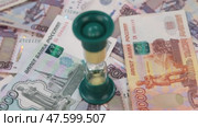 Вращение песочных часов, стоящих на фоне рублей. Концепция обратного отсчета времени и бизнеса. Стоковое видео, видеограф Александр Собко / Фотобанк Лори