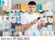 Attentive young guy client choosing box of paracetamol antipyretic pills, scan QR code on label, looking at composition of medicine in drug store. Стоковое фото, фотограф Яков Филимонов / Фотобанк Лори