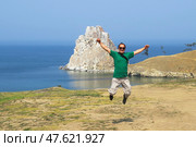 Joyful leap with Shaman Rock in Background at Lake Baikal, Russia. Стоковое фото, фотограф Ирина Кононова / Фотобанк Лори