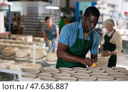 Man potter polishing new crafted plates. Стоковое фото, фотограф Яков Филимонов / Фотобанк Лори