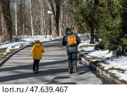 A little boy in bright yellow clothes and his dad ride scooters. A happy child and father are walking outside in early spring. Happy childhood and family. Стоковое фото, фотограф Photojuli / Фотобанк Лори