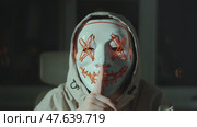 Masked figure in tech hoodie sits quietly with finger to lips, symbolizing digital protest, secret action or virtual resistance. Artistic expression of anonymous voice in online activism. Стоковое видео, видеограф Енваев Андрей / Фотобанк Лори