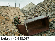На территории рудника, бывшего сталинского лагеря " Аляскитовый ". На переднем плане - железная тележка, на которой заключенные перевозили на поверхности уже извлеченную  руду по рельсам, проложенным по насыпи их камней. Мы видим эту тележку теперь, лежащую под откосом той самой насыпи.   Лагерь находился в отдаленном районе Якутии,  между Якутском и Магаданом. В этот лагерь направляли так называемых политических заключенных по 58 статье УК РСФСР ( враг народа ). В недрах добывалась горная руда, извлекалась на поверхность, и направлялась на обогатительную фабрику, которая находилась рядом. (2010 год). Редакционное фото, фотограф Павел Просянов / Фотобанк Лори
