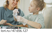 Crafting session features tools, UV resin, and various embellishments as mother guides daughter in creating custom trinkets. Artistic process strengthens their bond. Chemistry experiments at home. Стоковое видео, видеограф Енваев Андрей / Фотобанк Лори