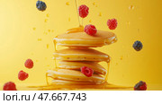 Pancakes stacked high with berries and syrup on a bright yellow background. Блинчики с ягодами и сиропом на ярко-желтом фоне. Стоковое AI-изображение, AI-художник Katsiaryna Repich / Фотобанк Лори