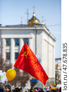 Магадан, Магаданская область, Россия. Политические активисты с красным флагом Советского Союза на первомайской демонстрации. Вдалеке купола православной церкви. 1 мая - Праздник весны и труда. (2018 год). Редакционное фото, фотограф Андрей Степанов / Фотобанк Лори