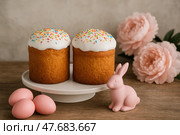 Пасхальный сет. Пасхальные куличи с глазурью, пасхальные яйца и пасхальный кролик на фоне цветов. Стоковое AI-изображение, AI-художник Башкирова Анна / Фотобанк Лори