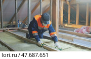 Insulation of a frame house with mineral wool. Cutting, fitting, laying insulation. Construction works. Стоковое видео, видеограф Константин Мерцалов / Фотобанк Лори
