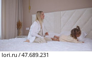 Attractive young woman and little cute girl are spending time together in bedroom at home. Mother with baby daughter lying on bed, hugging and having fun. Happy family concept. Mother's day footage. Стоковое видео, видеограф Ирина Михайличенко / Фотобанк Лори