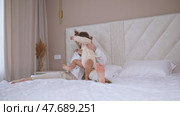 Attractive young woman and little cute girl are spending time together in bedroom at home. Mother with baby daughter jumping on bed, hugging and having fun. Happy family concept. Mother's day. Стоковое видео, видеограф Ирина Михайличенко / Фотобанк Лори