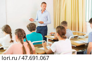 Teacher conducting lesson for teenage schoolchildren in classroom. Стоковое фото, фотограф Яков Филимонов / Фотобанк Лори