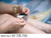 Female hands carefully peel off the protective film from an electrode of a muscle stimulator, preparing for use. Focus on the process of applying the device for muscle therapy. Стоковое фото, фотограф Татьяна Степанищева / Фотобанк Лори