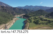 Turquoise Llosa del Cavall Reservoir on Cardener River winding through picturesque mountainous landscape in Catalonia, Spain, surrounded by lush greenery and rocky cliffs under clear blue sky. Стоковое видео, видеограф Яков Филимонов / Фотобанк Лори