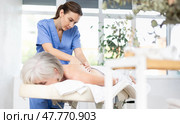 Professional young masseuse doing back massage to elderly woman. Стоковое фото, фотограф Яков Филимонов / Фотобанк Лори