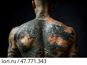 A man's back with a spectacular Japanese-style tattoo depicting a sinister dragon, spreading from the shoulders to the waist. The dragon is made with high detail: powerful scaly forms, an expressive head, sharp teeth, bright eyes and swirls of clouds around. Against the dark background, the composition looks especially powerful and dramatic. The photo emphasizes the art of tattooing, masculinity and symbolism of Eastern culture. An excellent choice for themes related to tattoos, Japanese culture, self-expression and body art. Стоковое AI-изображение, AI-художник Анна Кривицкая / Фотобанк Лори