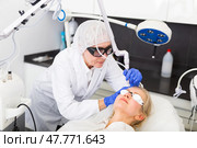 Cosmetologist making laser mole removal procedure for young woman. Стоковое фото, фотограф Яков Филимонов / Фотобанк Лори