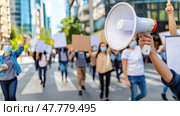 Group of individuals walking down a street carrying various signs and using a megaphone to amplify their message. Стоковое AI-изображение, AI-художник Данила Большаков / Фотобанк Лори