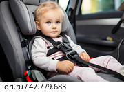 The child is sitting in the car, securely fastened with seat belts in the car seat. Стоковое AI-изображение, AI-художник Ирина Старикова / Фотобанк Лори