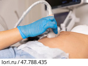Close up ultrasound scanner device in the hand of a professional doctor examining pregnant woman patient, doing abdominal ultrasound scanning. sonogram, sonography, sonographer, early pregnancy. Стоковое фото, фотограф Ирина Михайличенко / Фотобанк Лори