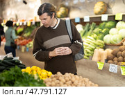 Male shopper carefully selects fresh bananas in grocery supermarket. Стоковое фото, фотограф Яков Филимонов / Фотобанк Лори