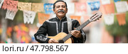 Cinco de Mayo mariachi musician with guitar in traditional suit and festive papel picado. Стоковое AI-изображение, AI-художник Анастасия Золотницкая / Фотобанк Лори