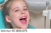 Happy little girl having dentist's appointment in modern clinic. Patient, adorable smiling child sitting in dentist's chair during appointment in pediatric dentistry clinic. Slow motion footage. Стоковое видео, видеограф Ирина Михайличенко / Фотобанк Лори