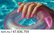 Woman's hand with sparkling nails resting on a pink pool float in summer sun. Женская рука с розовыми ногтями лежит на розовом поплавке в бассейне под летним солнцем. Стоковое AI-изображение, AI-художник Katsiaryna Repich / Фотобанк Лори