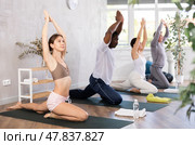 Woman doing Ardha Kapotasana with raised hands during group yoga. Стоковое фото, фотограф Яков Филимонов / Фотобанк Лори