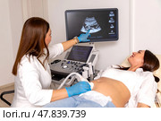Happy pregnant woman lying in hospital ward has uterus utltrasonographic diagnosis - female doctor scans her uterus and shows on screen. Стоковое фото, фотограф Ирина Михайличенко / Фотобанк Лори