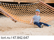 Summer lifestyle. A cute little boy is having fun playing in a hammock on the beach on a modern playground. The concept of family entertainment and leisure. Стоковое фото, фотограф Photojuli / Фотобанк Лори