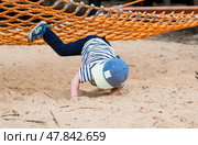 Lifestyle. Child safety. A cute little boy fell from a swing, hammock on a modern playground. The concept of caring for young children. Стоковое фото, фотограф Photojuli / Фотобанк Лори