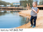 Summer lifestyle. A cute little boy is having fun playing with sand on the beach by the water. The concept of family entertainment and leisure. Стоковое фото, фотограф Photojuli / Фотобанк Лори