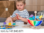 Balancing toys. A little boy is playing educational games. Children's wooden umbrella toy, colored pyramid and logic toys for children. Montessori games for child development. Стоковое фото, фотограф Photojuli / Фотобанк Лори