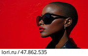 A confident woman with short hair and bold makeup poses in front of a red wall, flaunting her sunglasses and stylish outfit. Стоковое AI-изображение, AI-художник Данила Большаков / Фотобанк Лори