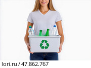 A Girl in plain colors T-shirt carries a box of recyclables. Стоковое AI-изображение, AI-художник Ирина Ручушкина / Фотобанк Лори