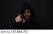 Mysterious lowkey portrait of a hooded individual with an emphatic gesture in dramatic lighting. Стоковое AI-изображение, AI-художник Андрей Бакусов / Фотобанк Лори