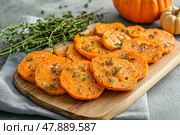 Cutting Fresh Pumpkins on Board with herbs. Baked pumpkin. Sliced raw Cucurbita and spices for preparing soup, warm salad, fall dish. Thanksgiving food. Roasted vegetable in olive oil salt , napkin. Стоковое AI-изображение, AI-художник Марина Демидюк / Фотобанк Лори