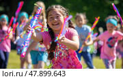 Children playing outdoors with vibrant, colorful streamers, running, laughing, and twirling around in a joyful and energetic manner. Стоковое AI-изображение, AI-художник Данила Большаков / Фотобанк Лори