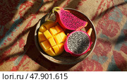 Freshly sliced mango and dragon fruit arranged beautifully on a plate. Свежее манго и драконий фрукт, нарезанные ломтиками, красиво разложены на тарелке. Стоковое AI-изображение, AI-художник Katsiaryna Repich / Фотобанк Лори