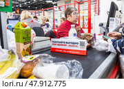 Продавец обслуживает покупателей на кассе в супермаркете Ашан. Редакционное фото, фотограф FotograFF / Фотобанк Лори