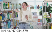 Woman choosing perfume in supermarket while standing near shelves with household goods. Стоковое видео, видеограф Яков Филимонов / Фотобанк Лори