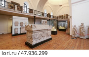 Ancient carved Roman sarcophagus displayed alongside marble statues in National Archaeological Museum of Sofia, showcasing historical artifacts from antiquity. Редакционное видео, видеограф Яков Филимонов / Фотобанк Лори