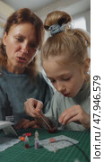 Mother and daughter create art pieces using UV resin at home, experimenting with colors, glitter, and forms on green cutting mat. Family creativity concept, safe home crafting, bonding activity. Стоковое видео, видеограф Енваев Андрей / Фотобанк Лори